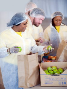 A group of people wearing gloves, aprons, and hair net prep food for shipping as part of their gig work.